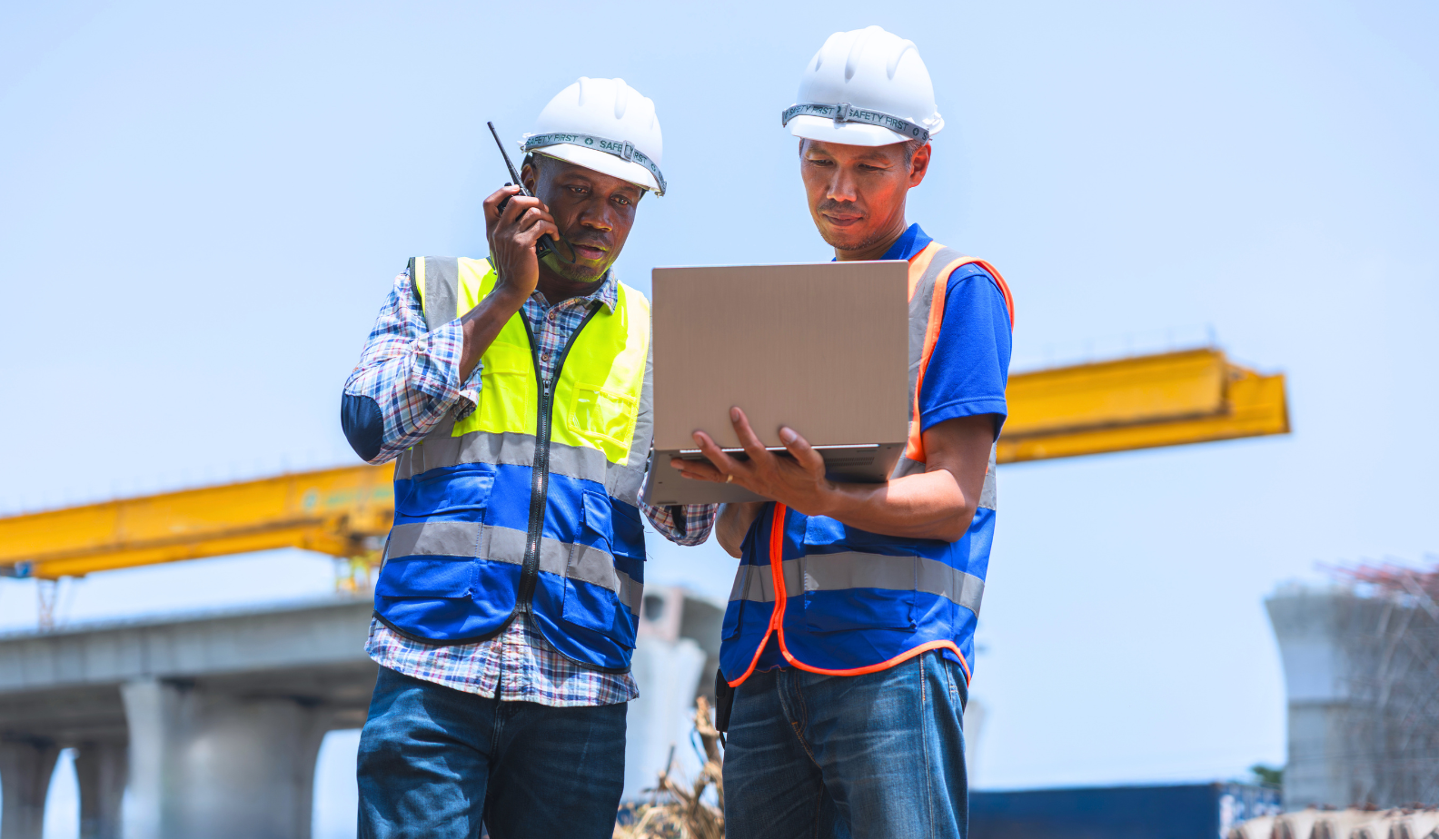 Project Managers work on their laptop at a construction site